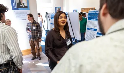 A student presenter presents their presentation to an audience member