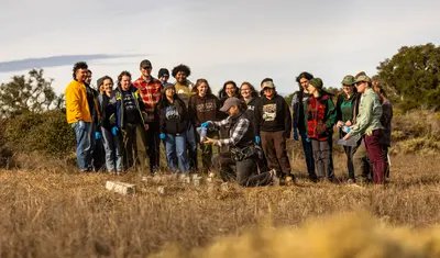A group of AES students look at their professor putting a field mouse into a bag.