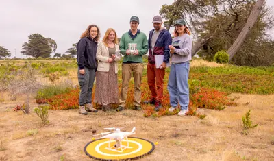 A group of AES students standing together setting up a drone to survey the area