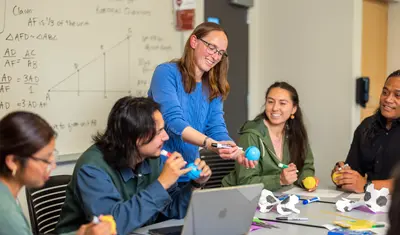 Professor interacting with students while teaching them a math concept.