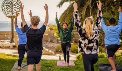 Students participating in a yoga session by the sea