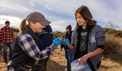 An AES professor hands over a field mouse to a student.