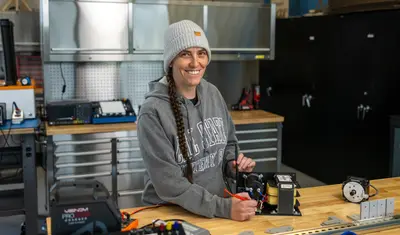 A mechatronics student smiling at the camera while working