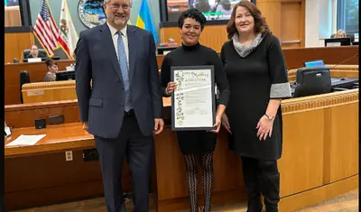 rachelle is flanked by a man and woman holding certificate