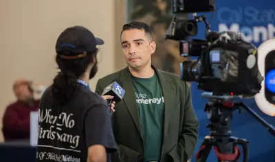 A news crew member interviewing a faculty member and recording it.