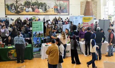 Lots of booths with people walking by at a career fair.