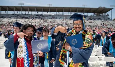 Graduates celebrate Commencement at Cal State Monterey Bay, proudly displaying their diplomas during a joyful outdoor ceremony that honors achievement, community and transformative education.