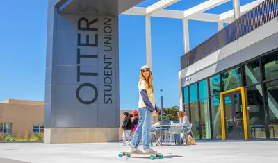 Student on skateboard outside buiding