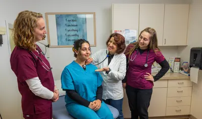 A professor providing an example of an exam on a nurse to other nurses around.