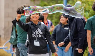Student making large bubbles with a bubble wand