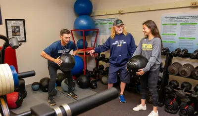 Students with teacher in gym lifting weights