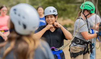 Student adjusting helmet to walk the high ropes