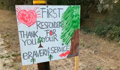 Kids from Girl Scout Troop 32096, some of whom have family who are firefighters, made roadside signs thanking those fighting the fires.