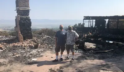 Chip Lenno (left) and Kevin Cahill stand where their front door used to be. Behind them, the former living room, office and kitchen with a view of the Salinas Valley.