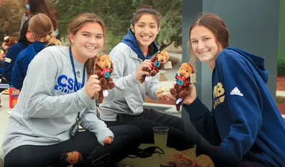 Photo: Three students smiling and holding otter plushies