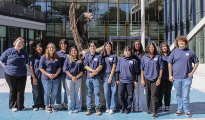 Students posing in front of Statue