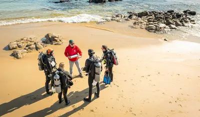 Students prepare for a coastal diving activity with an instructor, engaging in hands-on learning in the marine environment.