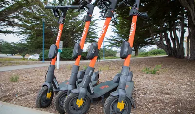 Spin scooters stand ready for riders outside the Alumni and Visitors Center on campus.