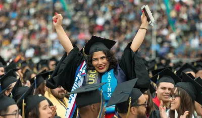 Photo: Graduate with Latinx stole, arms raised, cheering