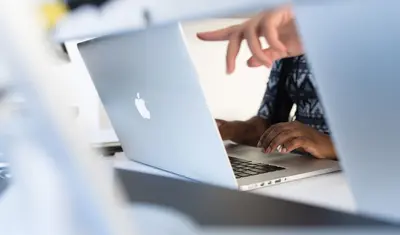 Photo: Women pointing at and using a Mac laptop