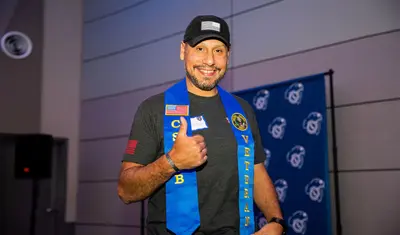 Student gives a thumbs up to the camera after the Veterans Stole Ceremony.