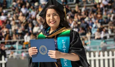 Latinx Grad holding diploma at the 2022 Commencement | Photo by Brent Dundore-Arias