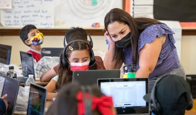 Photo: CSUMB student and co-teacher Gabriela Suarez answers a student’s question during a math lesson.