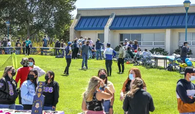 Photo: Students lining up at club and organization tables in the quad during the Otter Showcase event