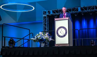 Photo: President Ochoa speaking at a podium during Day of Welcome employee event
