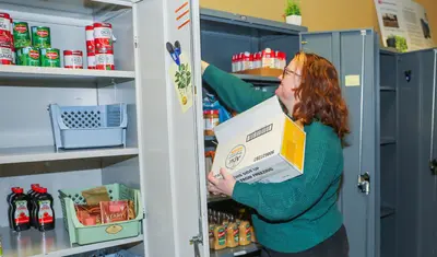 Basic Needs coordinator Robyn DoCanto stocks shelves in the pantry, which provides food-insecure students with important nutrition.