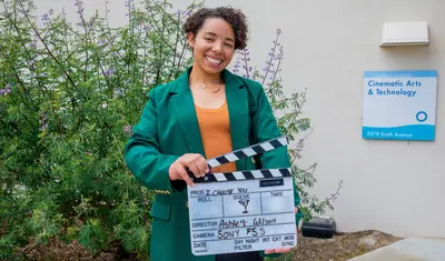 Ashley Wilson with film clapboard promoting her capstone film