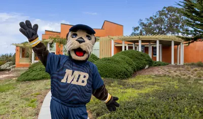 Monte Rey, CSUMB mascot, posing in front of the Alumni and Visitor Center Building