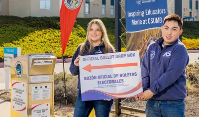 Nicole Hollingsworth and Javier Frias Origel next to an official ballot drop box