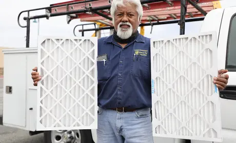 Augie Eclarin, from Facilities, holding a MERV 8 (left) and MERV 13 filters