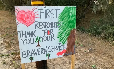 Kids from Girl Scout Troop 32096, some of whom have family who are firefighters, made roadside signs thanking those fighting the fires.