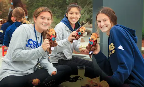 Photo: Three students smiling and holding otter plushies