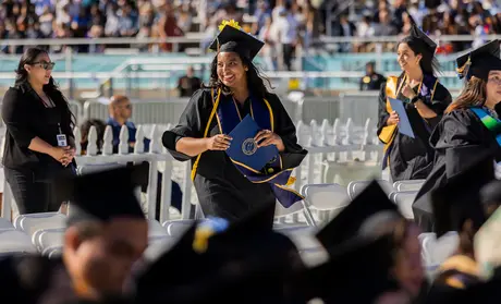 Photo: Graduate walking and holding diploma