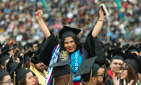 Photo: Graduate with Latinx stole, arms raised, cheering