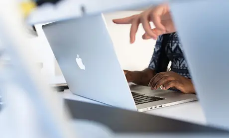 Photo: Women pointing at and using a Mac laptop