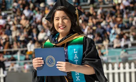 Latinx Grad holding diploma at the 2022 Commencement | Photo by Brent Dundore-Arias