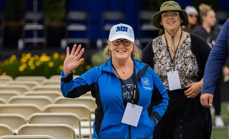Staff member waving at the camera during Commencement