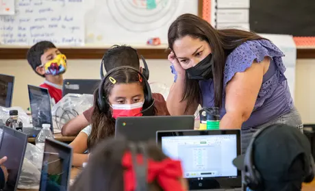 Photo: CSUMB student and co-teacher Gabriela Suarez answers a student’s question during a math lesson.