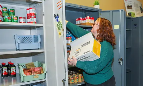Basic Needs coordinator Robyn DoCanto stocks shelves in the pantry, which provides food-insecure students with important nutrition.
