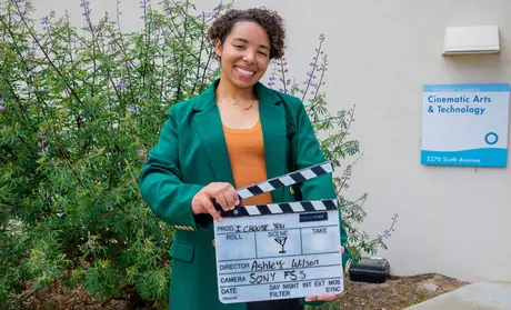 Ashley Wilson with film clapboard promoting her capstone film