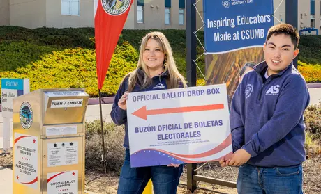 Nicole Hollingsworth and Javier Frias Origel next to an official ballot drop box