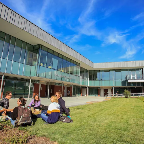 Group of students sitting on grass outside the CAHHS building