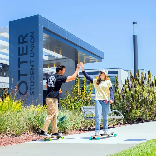 Two people hi fiving in front of the otter student union