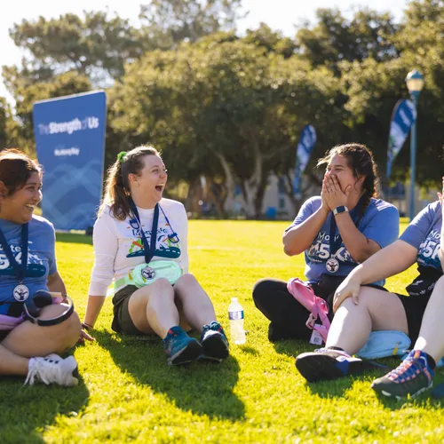 4 participants of MB madness sit together in a circle in the grass and laugh