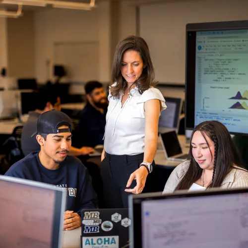 Dr. U assisting two students with statistics in a classroom setting