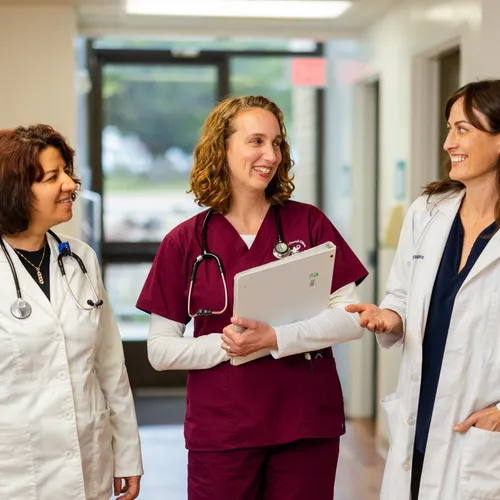 A nursing student in a scrub and two professors standing in a walkway talking together